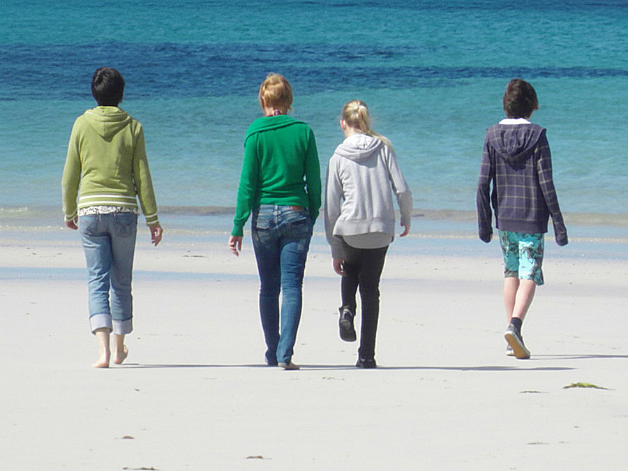Eine Mutter mit vier Teenagern von hinten auf dem Weg zum Meer